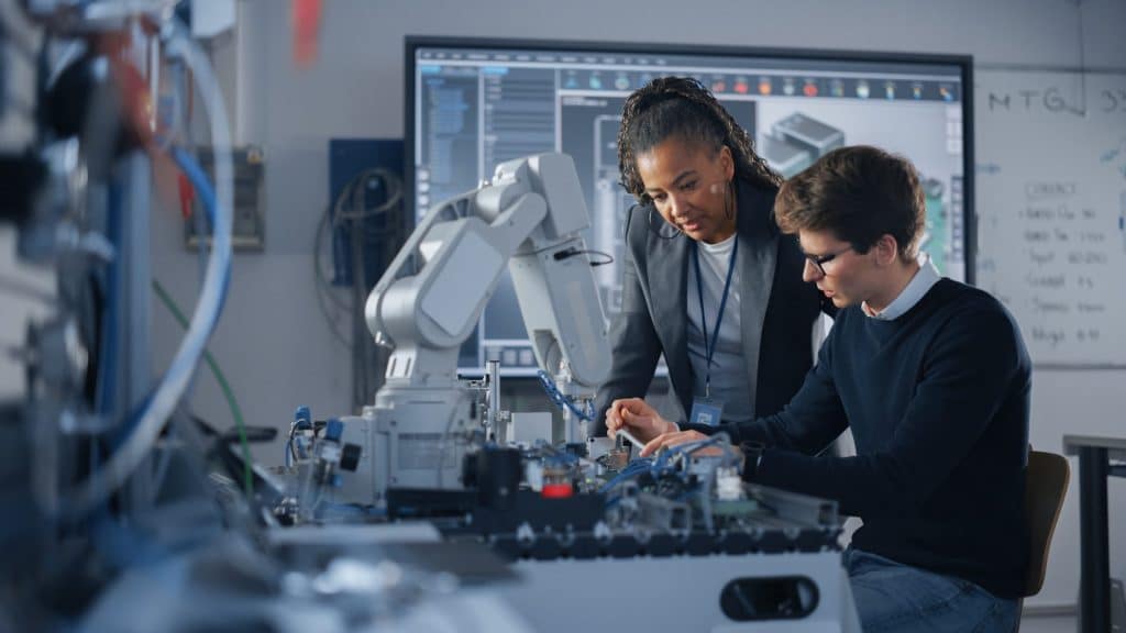 un jeune ingénieur discute avec sa supérieure devant un robot